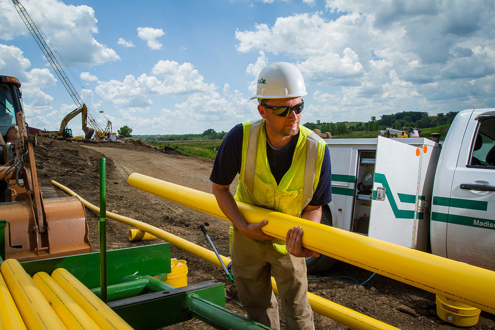 MGE employee unloading pipe for natural gas lines.