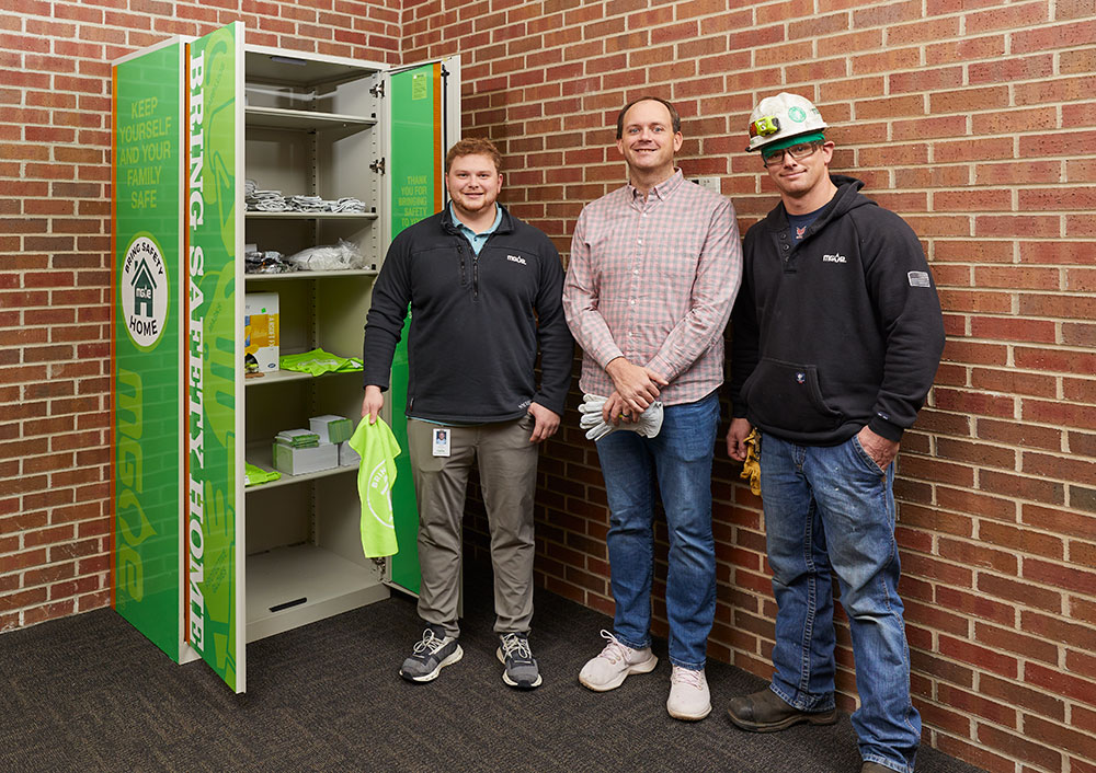 members of MGE's Bring Safety Home team stand beside the safety cabinet