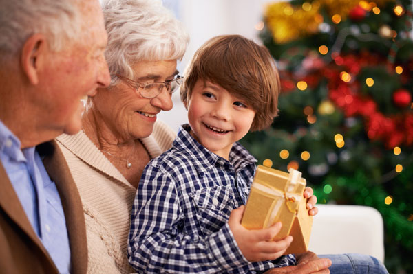 young boy with grandparents receiving gift at christmas