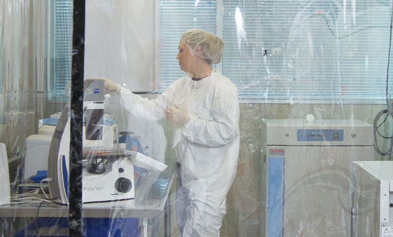 A lab technician works behind protective sheeting at the research company Primorigen Biosciences Inc., located in the UW Research Park.