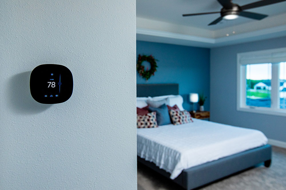 Bedroom with a smart thermostat on the wall of the left side of the image.