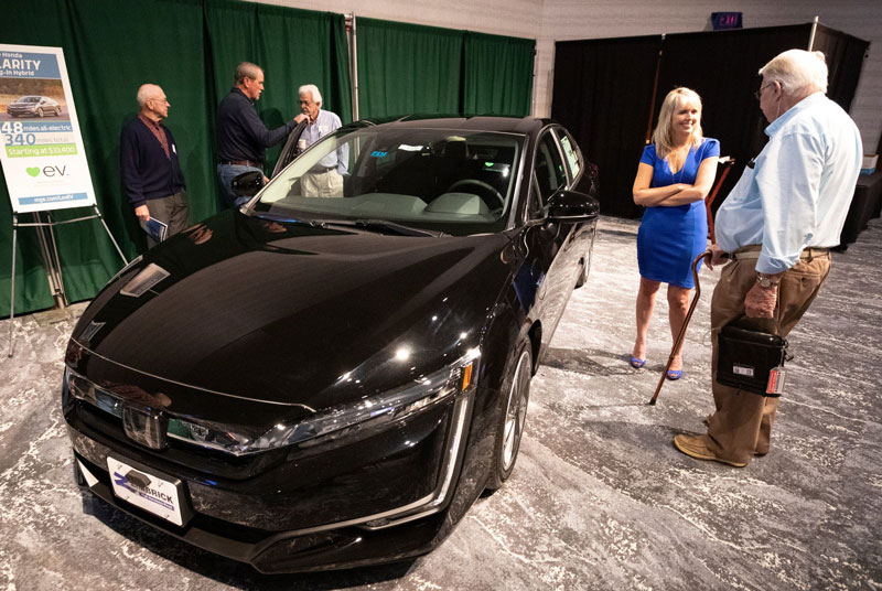 A shareholder talks with MGE's Debbie Branson in front of a plug-in hybrid Honda Clarity.