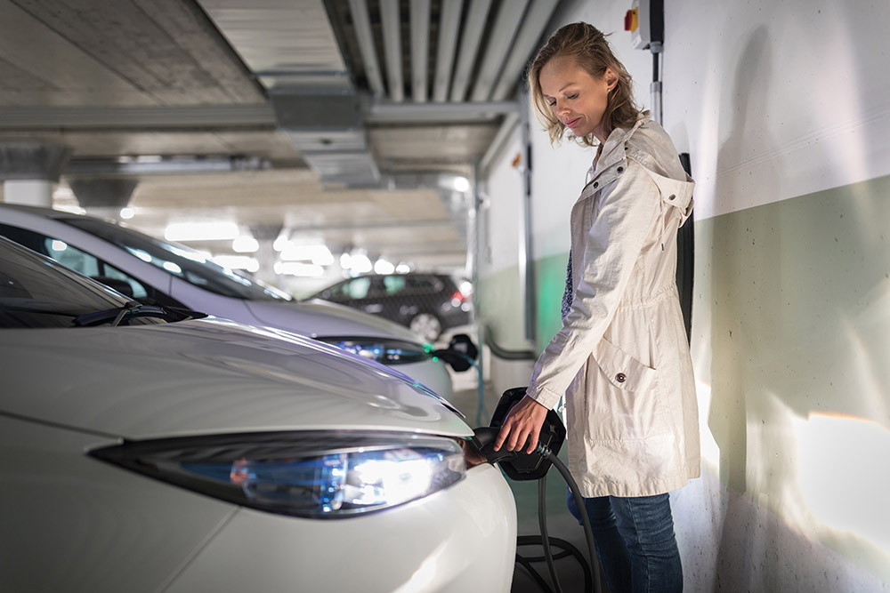 woman charging her EV in an apartment garage